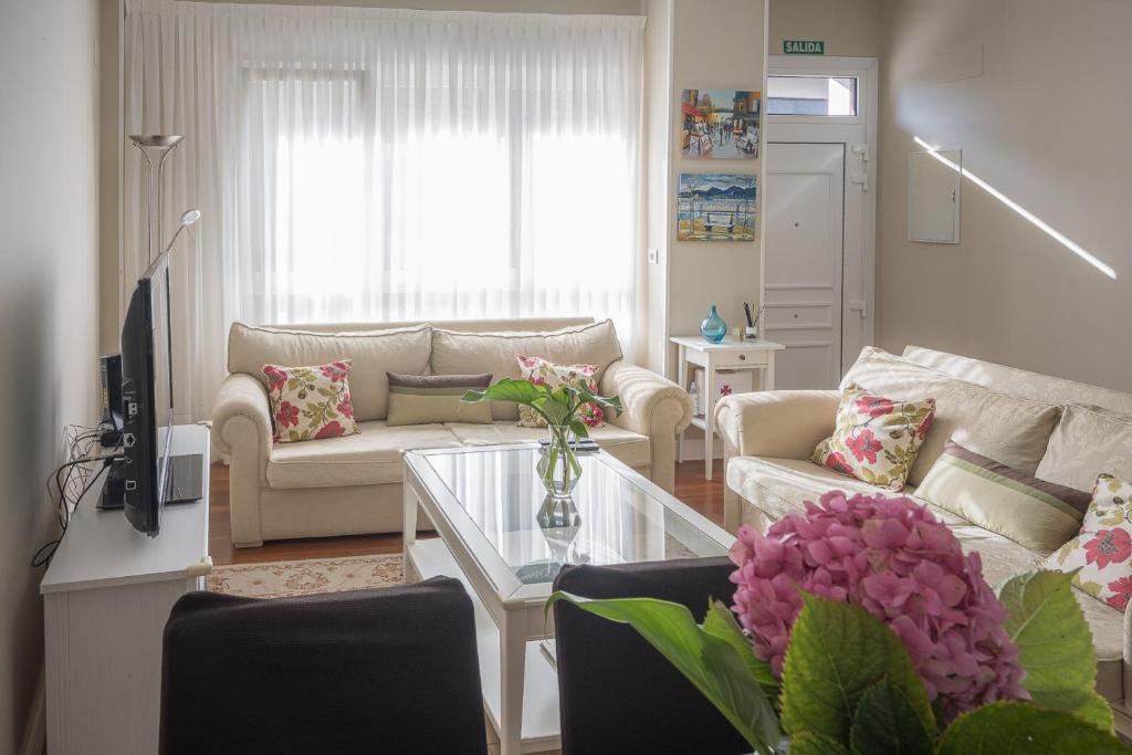 sala de estar con sofá y mesa con flores en Piso nuevo y espacioso en el centro de Mundaka, en Mundaka
