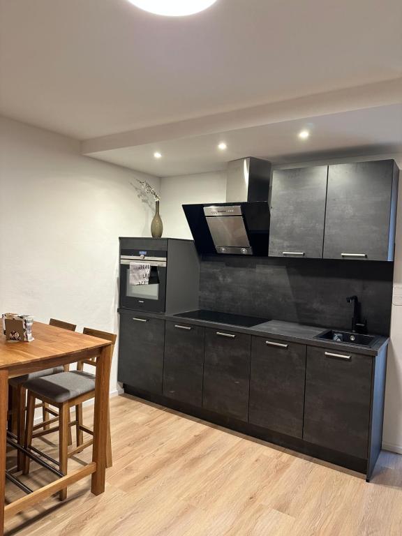 uma cozinha com armários pretos e uma mesa de madeira em City Apartment em Sankt Ingbert