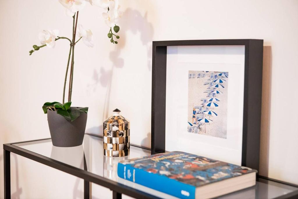 una mesa de cristal con un marco de imagen y un libro en Delightful shanti home en Milán