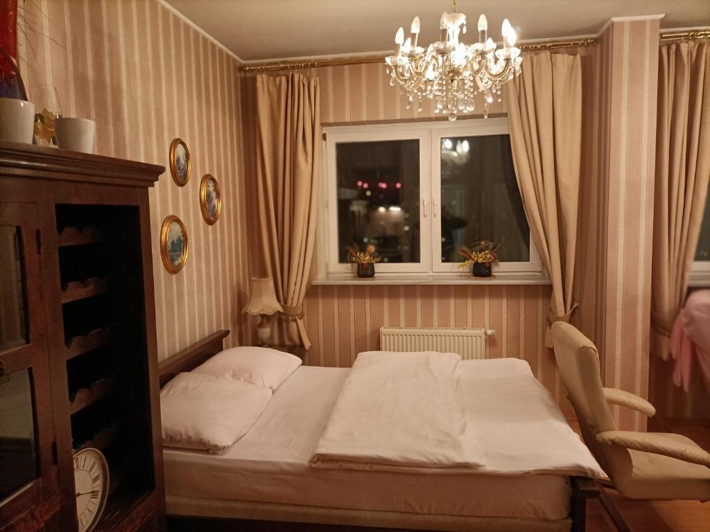 a bedroom with a bed and a window and a chandelier at Arkadia Centrum - Pokoje in Warsaw
