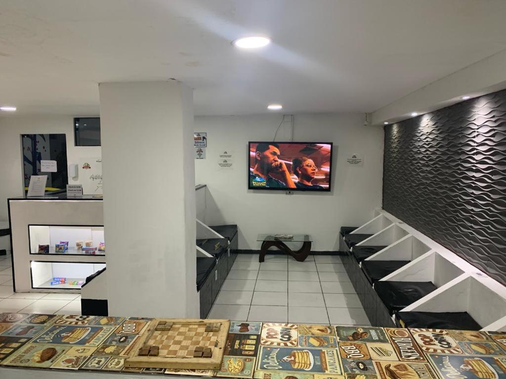 um quarto com prateleiras e uma televisão na parede em Estação Hostel - Em frente ao Metrô em São Paulo