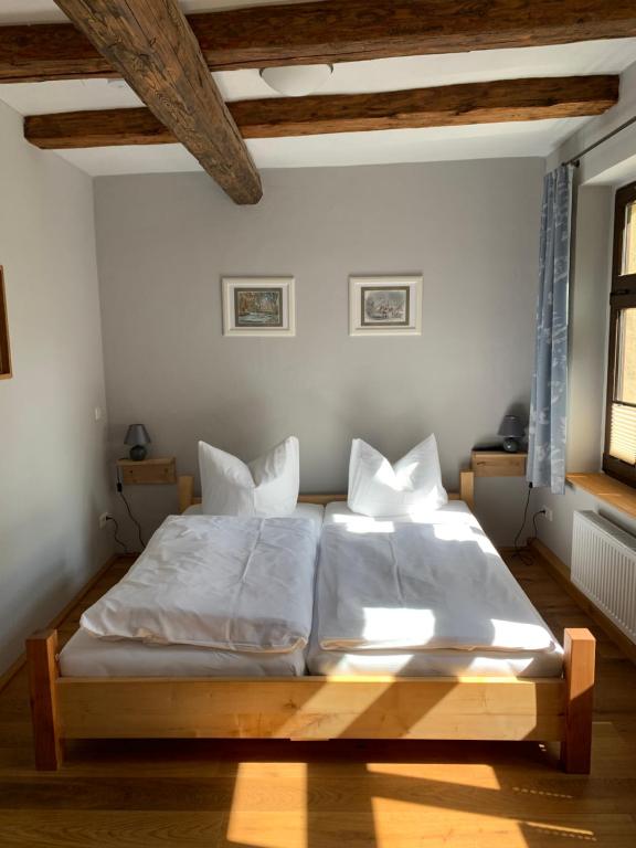 Schlafzimmer mit einem Bett mit weißer Bettwäsche und Kissen in der Unterkunft Ferienwohnungen an der Blasiikirche in Quedlinburg