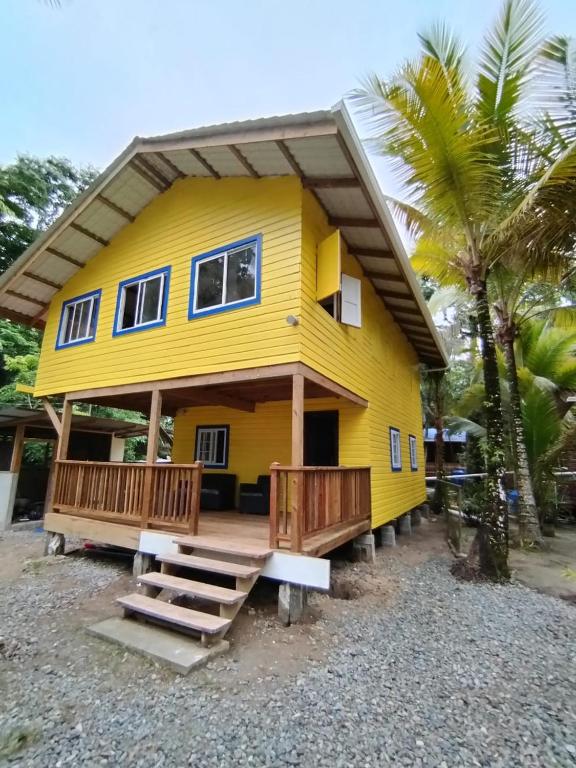 a yellow house with a large front porch and a porch at Hotel Tierra Verde Bed and Breakfast in Bocas del Toro