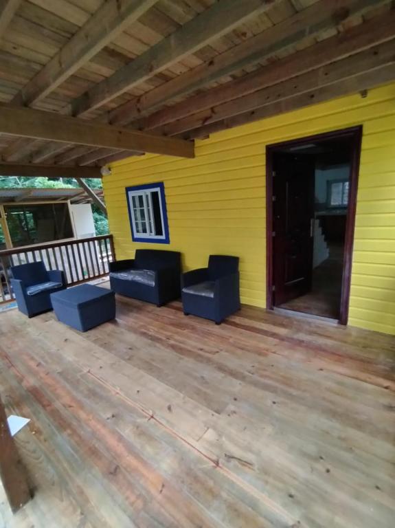 a yellow house with blue chairs on a wooden deck at Hotel Tierra Verde Bed and Breakfast in Bocas del Toro