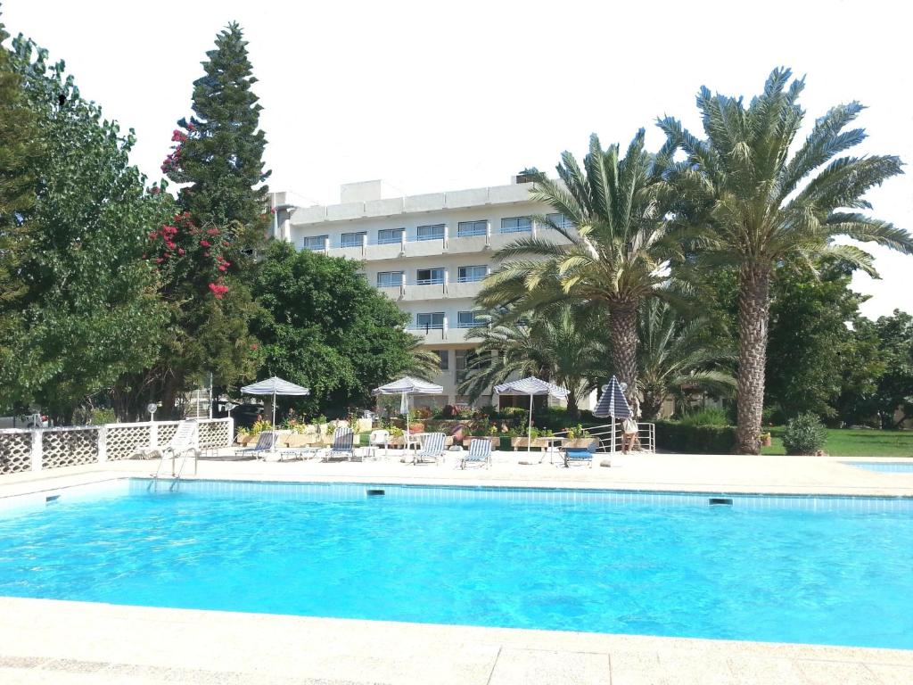 einen Pool vor einem Hotel mit Palmen in der Unterkunft Marion Hotel in Polis Chrysochous