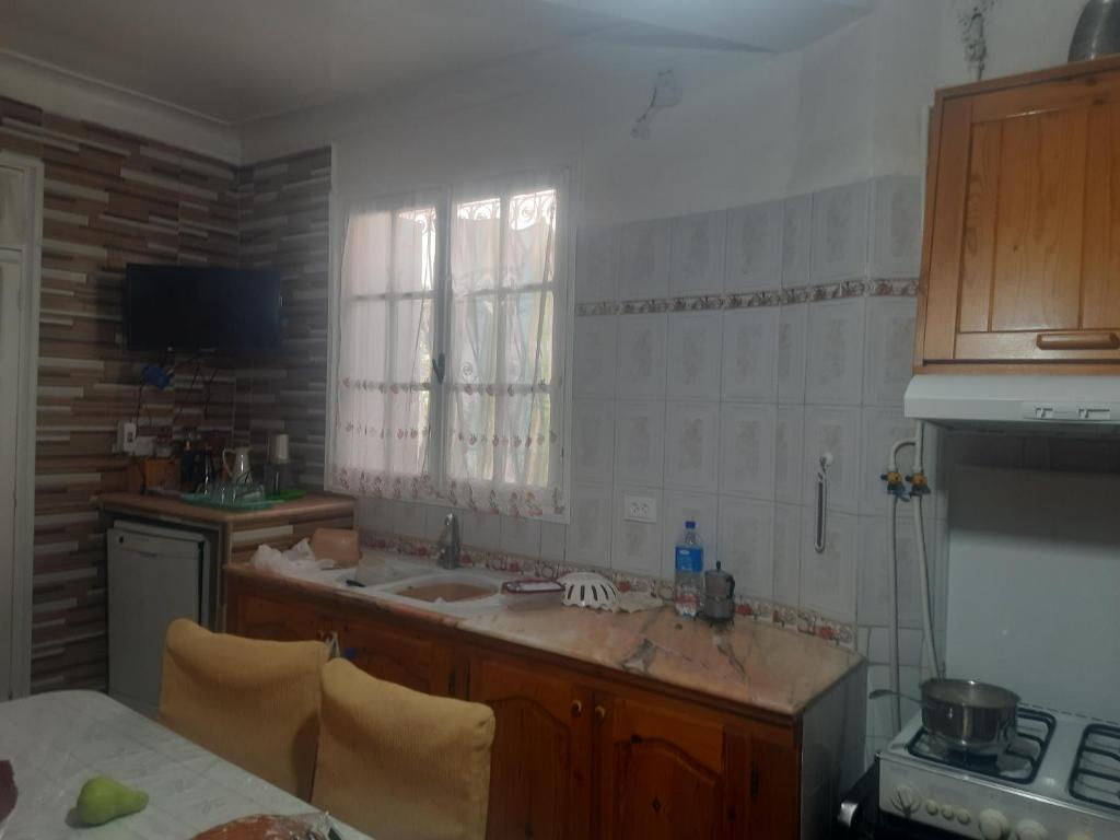 a kitchen with a counter and a sink and a window at Maison tranquille in Boumerdes