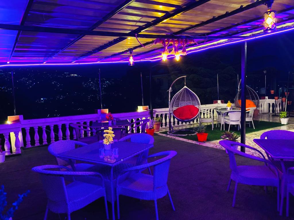 西姆拉的住宿－Hotel Tara INN with terrace and mountain view，餐厅配有紫色照明、桌子和秋千