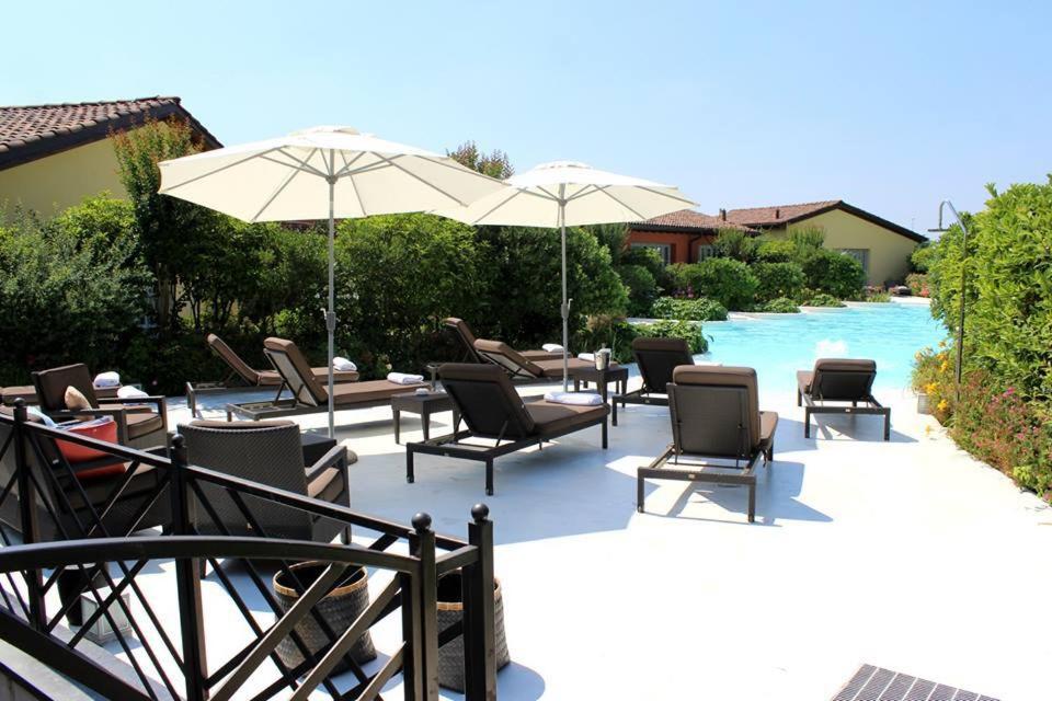 een patio met stoelen en parasols naast een zwembad bij Joia Hotel & Luxury Apartments in Brusaporto