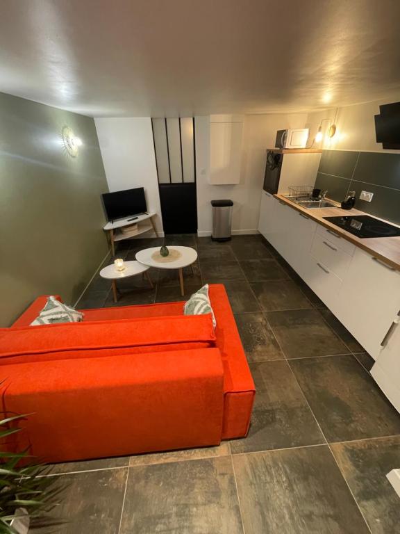 a living room with an orange couch and a kitchen at Gare australe in Saint-Brieuc