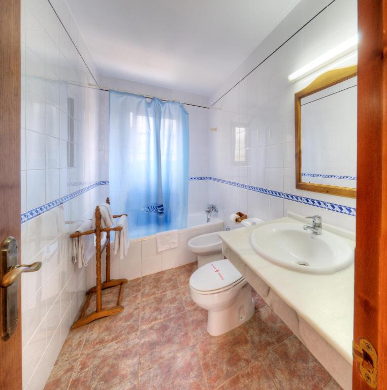 a white bathroom with a toilet and a sink at Hostal Alhambra in Zahora