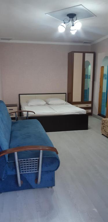 um quarto com uma cama e uma cadeira azul em Гостевой дом Анастасия em Sukhumi