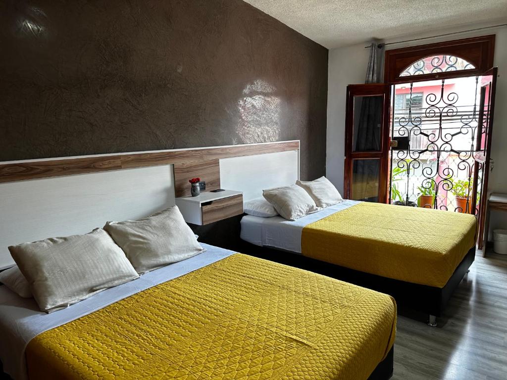 sypialnia z 2 łóżkami z żółtą pościelą i oknem w obiekcie Casa Marin Framboyan w mieście Oaxaca