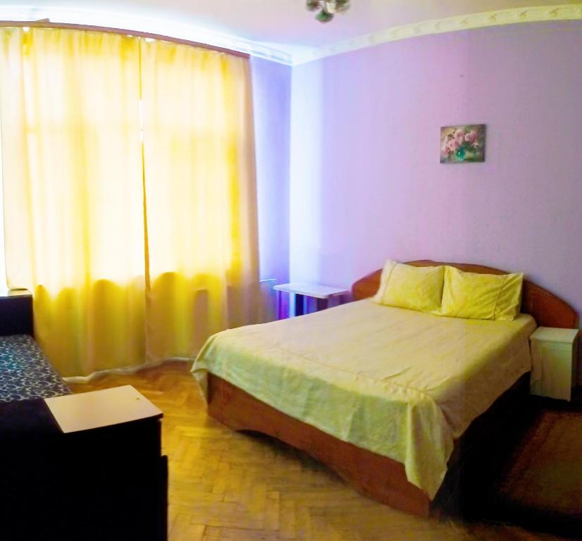 ein Schlafzimmer mit einem Bett und einem gelben Vorhang in der Unterkunft Затишна квартира в центрі Калуша in Kalush