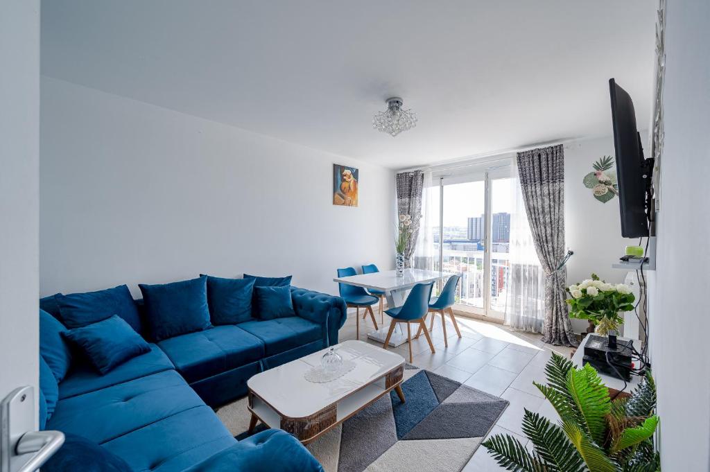 ein Wohnzimmer mit einem blauen Sofa und einem Tisch in der Unterkunft Perle Parisienne, Vue Captivante in Saint-Ouen