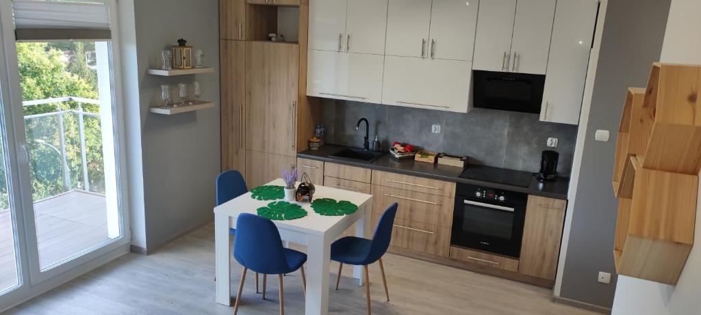 a kitchen with a white table and blue chairs at Apartament Pod Klonem in Bartoszyce