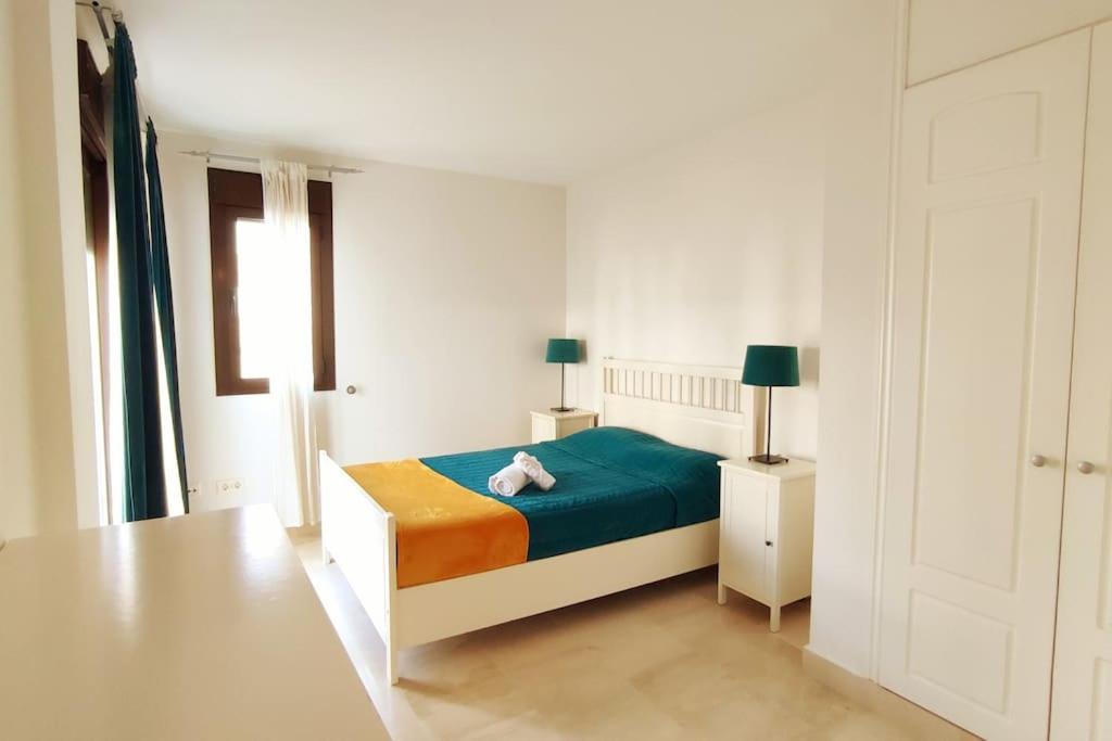 a white bedroom with a bed and a table at Apartamento en Birdie Club in San Roque