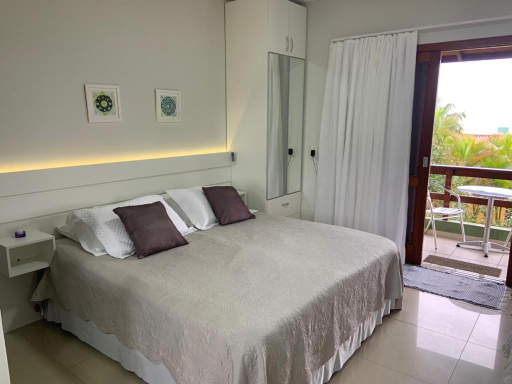 a white bedroom with a bed and a balcony at Pousada Mar de Cristal in Florianópolis