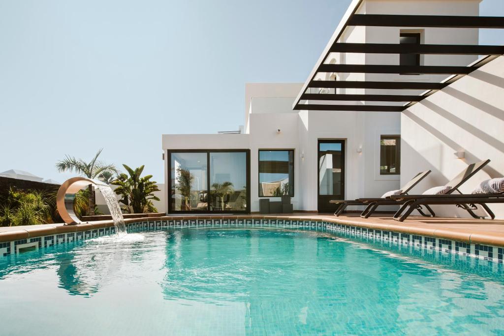 una piscina con 2 sillas y una casa en Villa Faro, en Playa Blanca