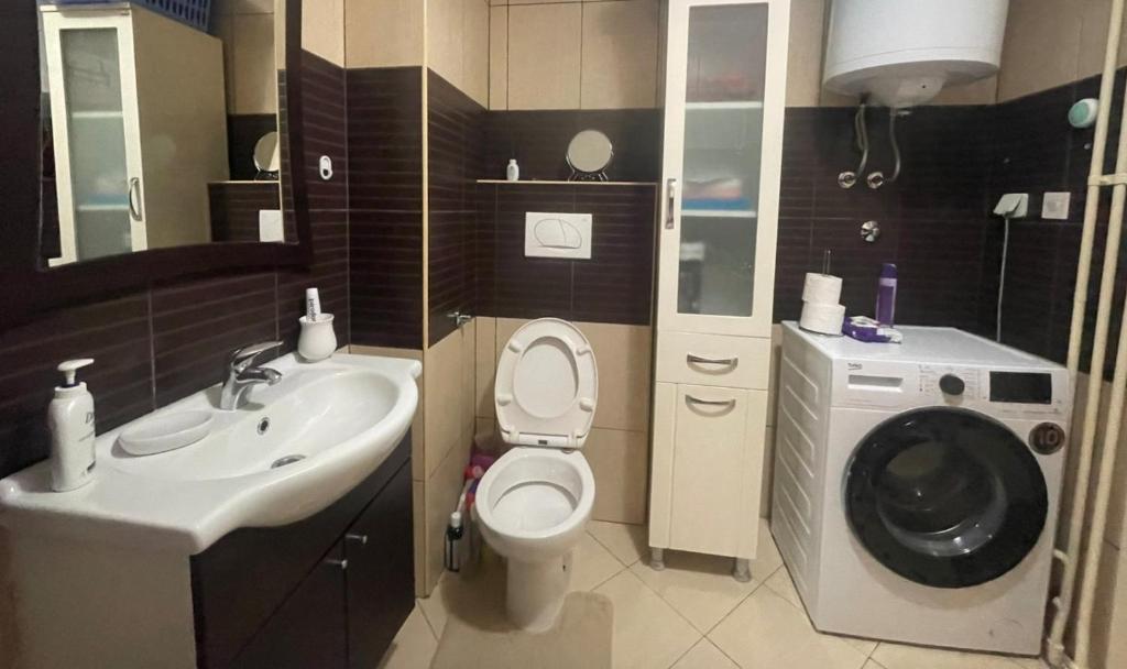 a bathroom with a toilet and a sink and a washing machine at Apartman Zenica in Zenica