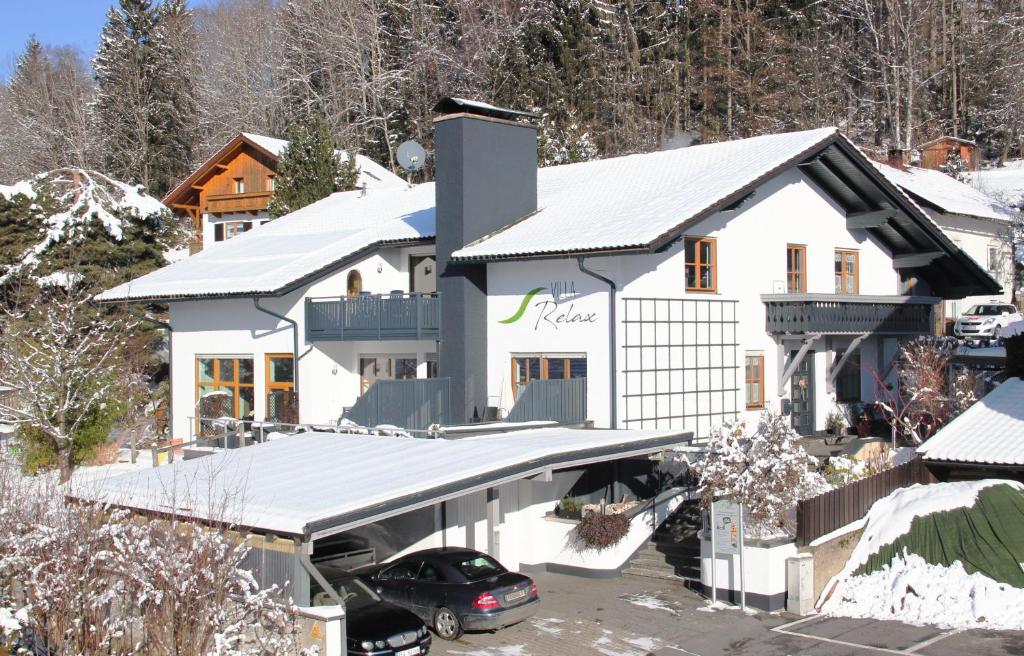 a white house with a car parked in a parking lot at Villa Relax - Ferienwohnungen & Hallenbad & Relaxgarten in Bodenmais