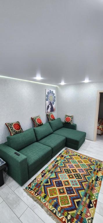 uma sala de estar com um sofá verde e um tapete em MIRAMEL HOME Centro em Yakkasaray