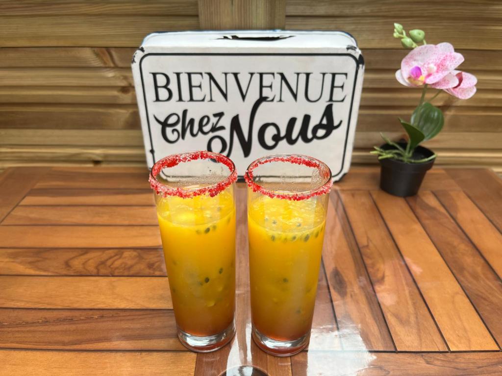 two glasses of orange juice on a table with a sign at Les Chalets de Marie & Steph 2 - Vue mer, Jacuzzi SPA privatif Sans vis à vis in Saint-Denis