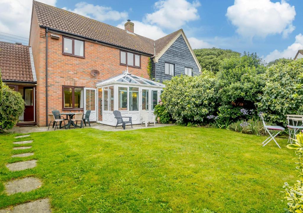 a house with a patio and a lawn at Rainbow Cottage in Thorpeness