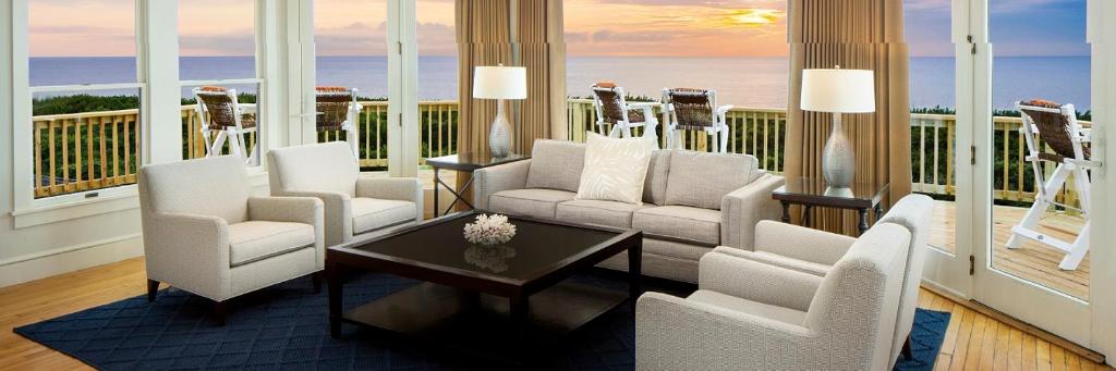 a living room with white chairs and a view of the ocean at Sanderling Resort Residences in Duck