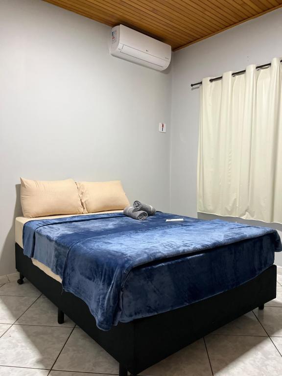 a bedroom with a bed with a blue blanket on it at Casa Iguaçu in Foz do Iguaçu