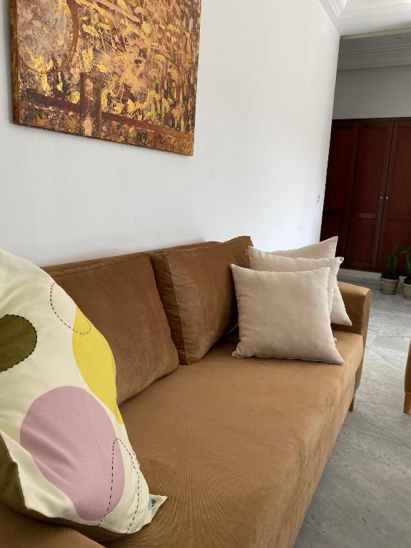 a brown couch with pillows in a living room at apartement Lac 2 in El Aouina