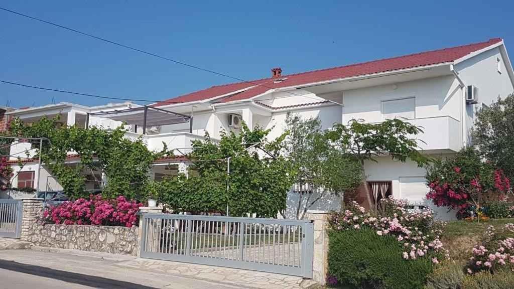 a white house with a white fence and flowers at Apartment Ljubac 1 in Ljubač