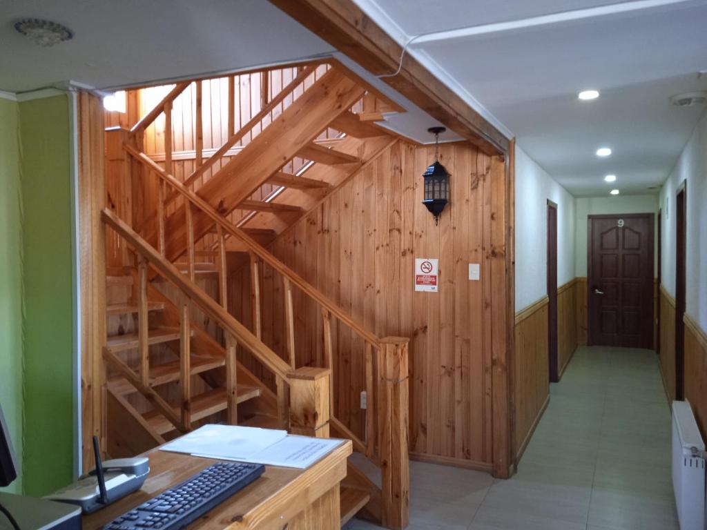 an office with a wooden staircase and a desk with a keyboard at Hostal JC in Puerto Natales