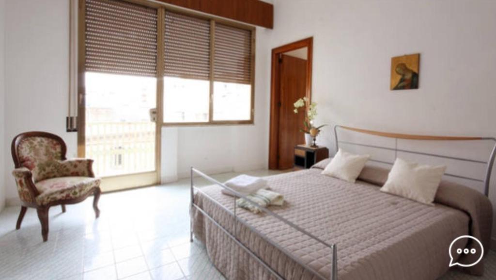 マルサラにあるPalazzo Bonventreのベッドルーム1室(ベッド1台、椅子、窓付)