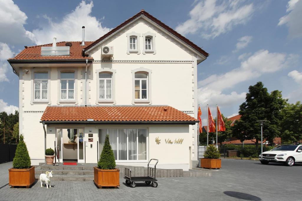 ein weißes Haus mit einem Hund davor in der Unterkunft Hotel Villa Will in Hannover