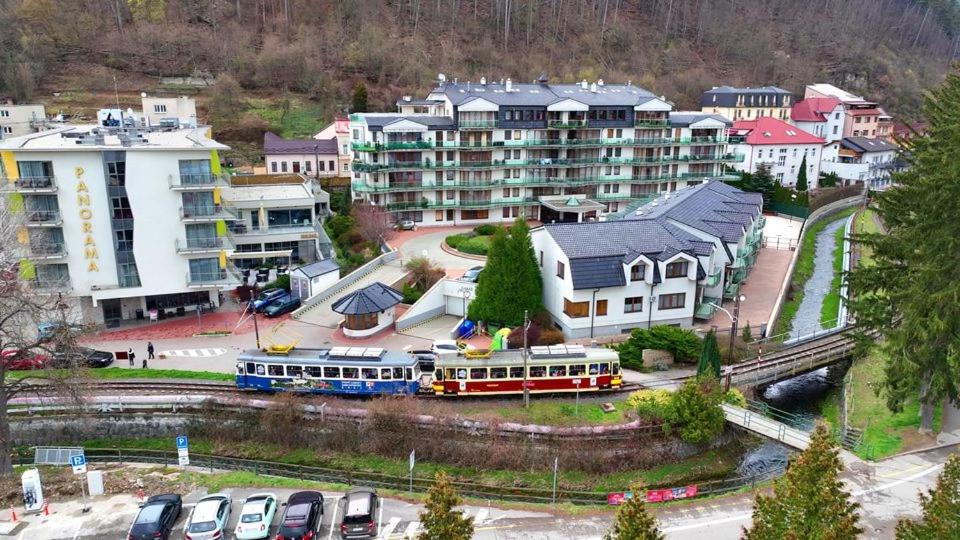 a city with a train and buildings and cars at Kristoff Plaza in Trenčín