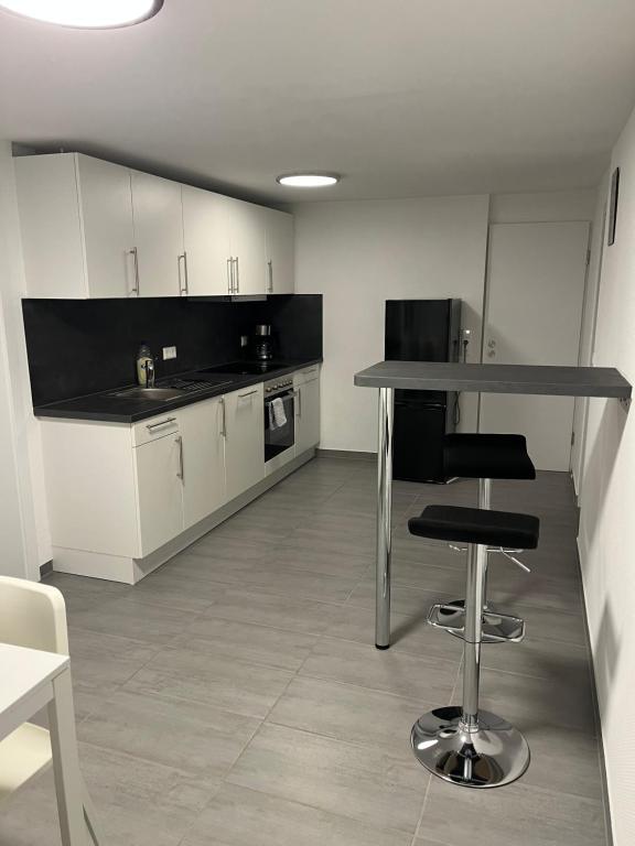 a kitchen with white cabinets and a table and stool at Home-for-you-Ferienwohnung Monteurwohnung in Buchen