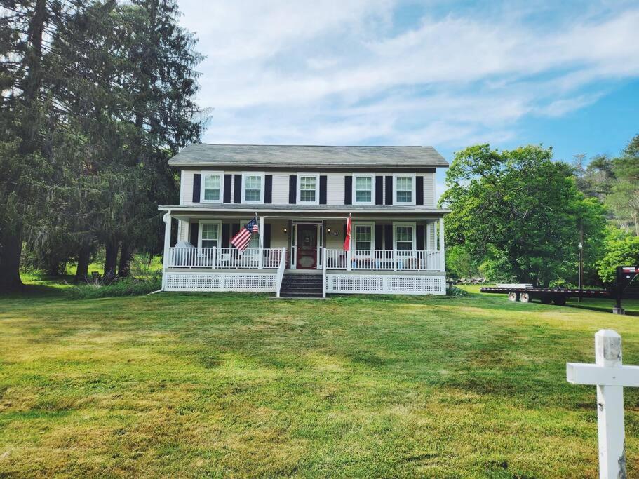 Ein weißes Haus mit amerikanischer Flagge auf einem Hof in der Unterkunft Historic American Farmhouse 1870 - 10 miles from Cherry Springs! in Coudersport
