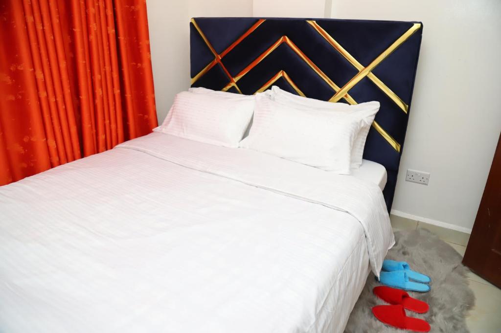 - une chambre avec un grand lit blanc et des rideaux rouges dans l'établissement My Cozy Home By BC, à Nairobi