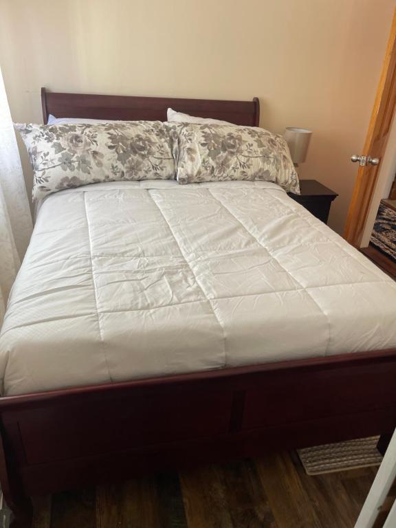 1 cama con edredón blanco en un dormitorio en Home away from home, en Laurelton