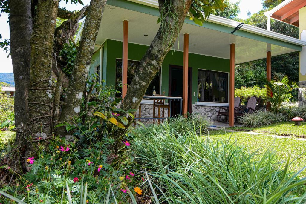 a green house with a tree and some flowers at Yanu’s casita in Guaria
