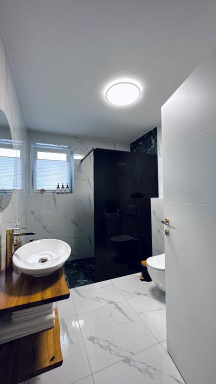 a white bathroom with a sink and a toilet at NewEra Apartment 1 