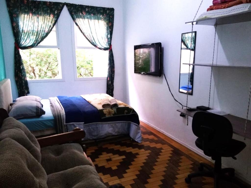 a bedroom with a bed and a desk and a window at Sobrado Tranquilo Centro in Porto Alegre