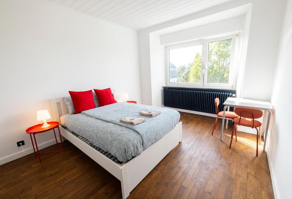 a bedroom with a bed with red pillows and a desk at Tram station rooms by CityPillow since 2019 in Hesperange
