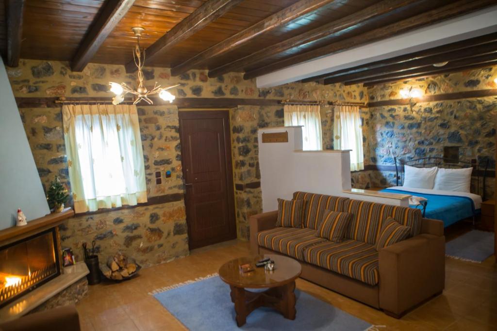 a living room with a couch and a bed at Suites Mouses in Palaios Agios Athanasios