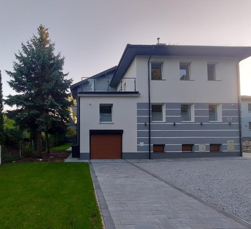 a white house with a garage and a tree at Willa Vistula in Ciechocinek