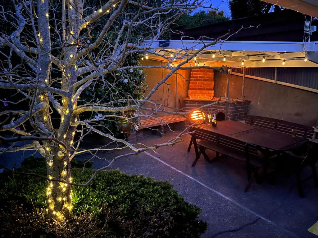 a patio with a table and a bench with lights at Retro 4 bedroom home, warm and welcoming, quiet location in Porirua