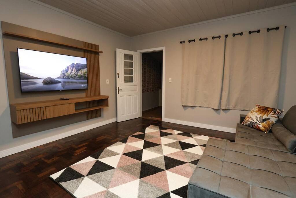 a living room with a television and a checkered floor at Casa no Centro de Concórdia - SC in Concordia