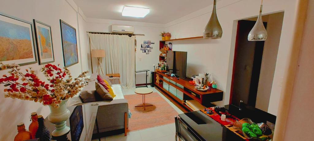 uma sala de estar com um sofá e uma mesa num quarto em Quarto e banheiro privativos com garagem fechada em apartamento aconchegante em Jardim da Penha em Vitória