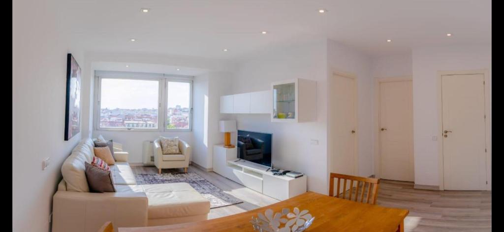 a white living room with a couch and a tv at Colón Vistas in Madrid
