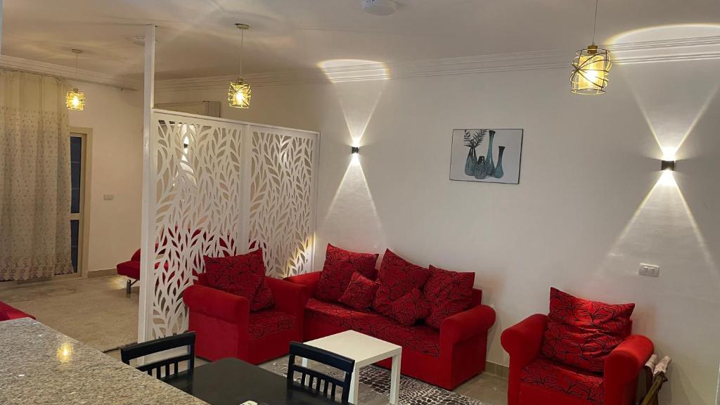 ein Wohnzimmer mit roten Stühlen und einem Sofa in der Unterkunft Red Ruby Compound منتجع الياقوتة الحمراء in Hurghada